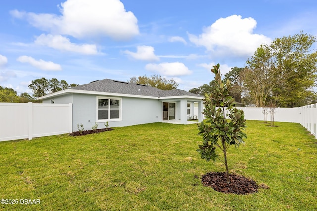 back of property featuring a shingled roof, a fenced backyard, a lawn, and stucco siding