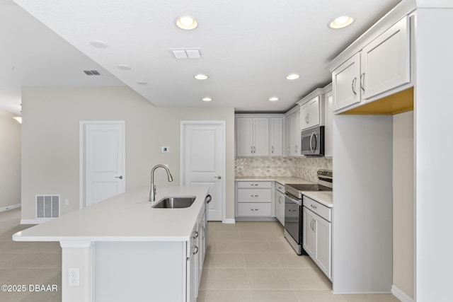 kitchen with a sink, stainless steel appliances, tasteful backsplash, and visible vents