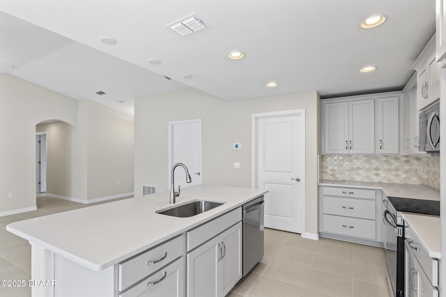 kitchen featuring visible vents, a center island with sink, light tile patterned flooring, a sink, and appliances with stainless steel finishes