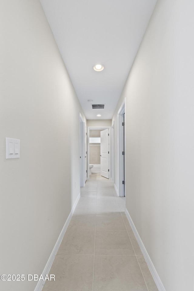 hallway with light tile patterned floors, visible vents, recessed lighting, and baseboards