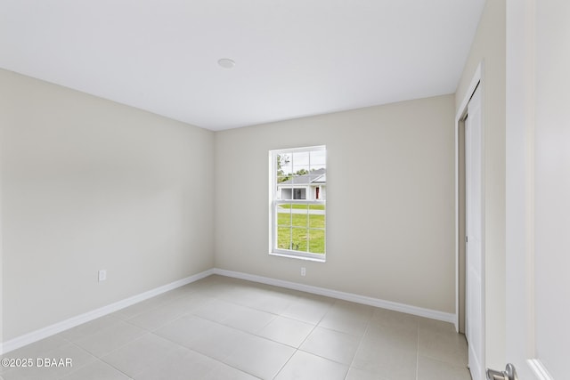 empty room featuring light tile patterned floors and baseboards