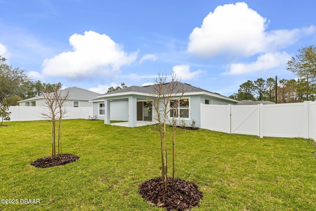 rear view of house featuring a gate, a yard, a fenced backyard, and stucco siding