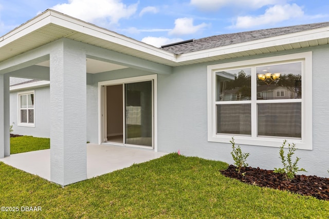 exterior space with stucco siding, a patio, and a yard