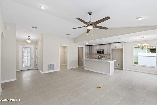 unfurnished living room featuring light tile patterned flooring, visible vents, ceiling fan with notable chandelier, and lofted ceiling