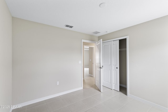 unfurnished bedroom featuring light tile patterned floors, visible vents, a closet, and baseboards