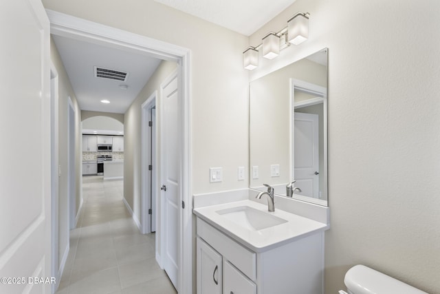 bathroom featuring vanity, visible vents, tile patterned flooring, toilet, and tasteful backsplash