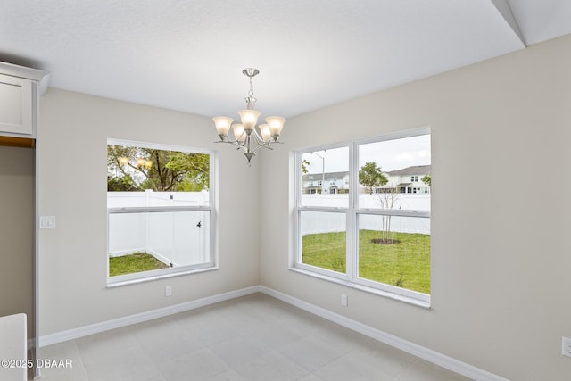 unfurnished dining area featuring an inviting chandelier and baseboards