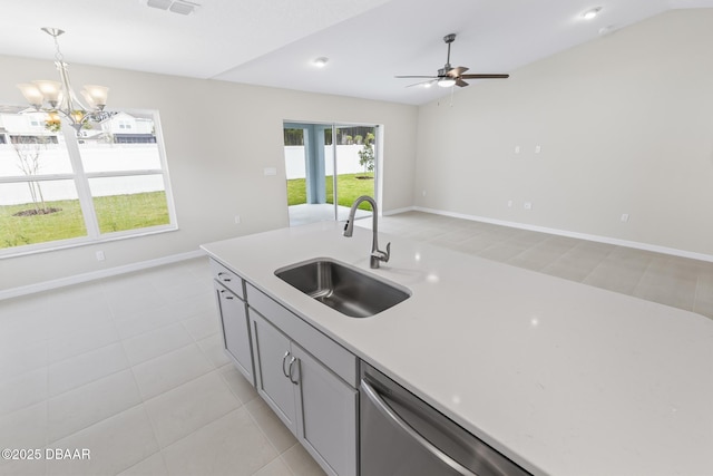 kitchen featuring ceiling fan with notable chandelier, a sink, stainless steel dishwasher, light countertops, and hanging light fixtures