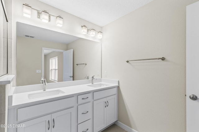 full bath with double vanity, baseboards, visible vents, and a sink