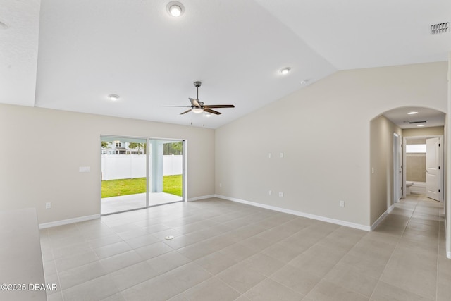 empty room featuring visible vents, a ceiling fan, arched walkways, baseboards, and vaulted ceiling