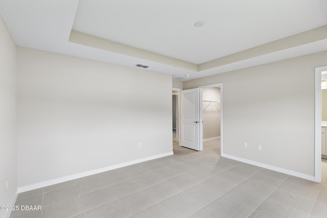 spare room featuring light tile patterned floors, visible vents, and baseboards