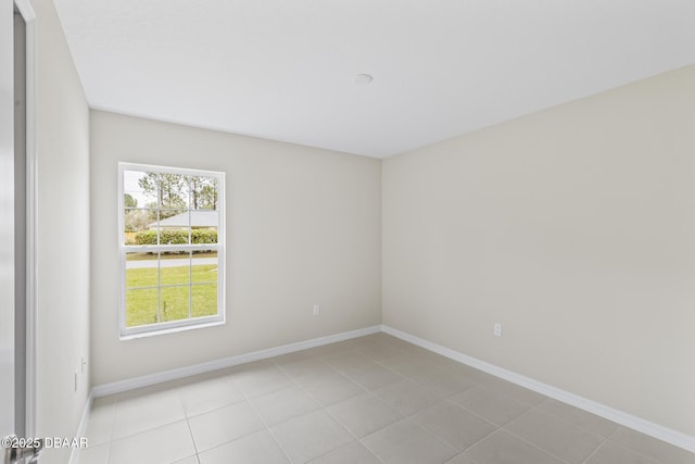 spare room featuring light tile patterned flooring and baseboards