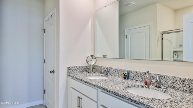 bathroom featuring a shower with shower door and vanity