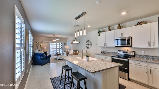 kitchen featuring stainless steel appliances, white cabinets, sink, a breakfast bar area, and a kitchen island with sink