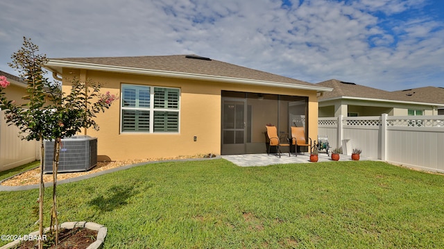 rear view of house with a patio, a sunroom, a yard, and central AC