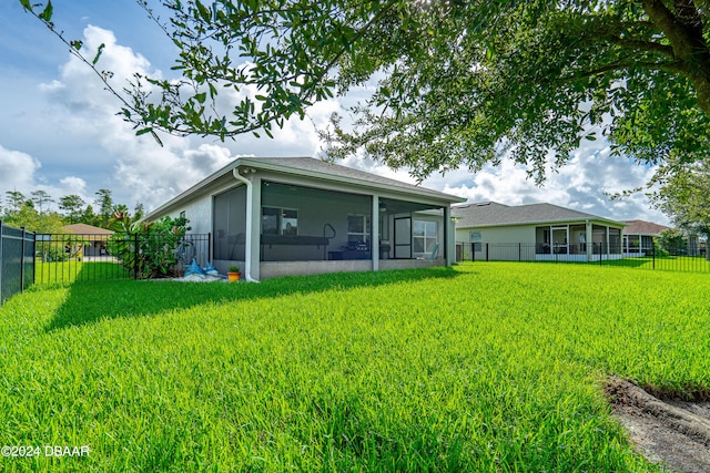 rear view of house featuring a sunroom and a yard