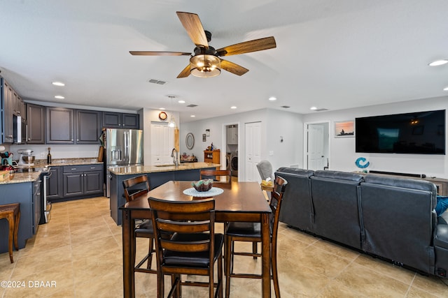 dining space featuring light tile patterned flooring, sink, ceiling fan, and washer / dryer