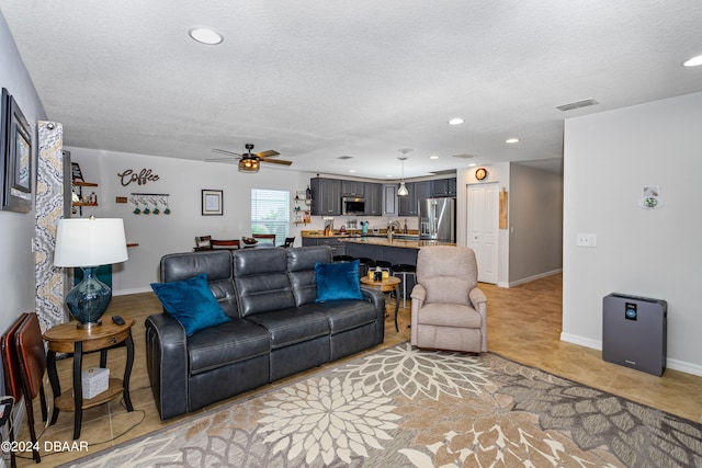 living room with ceiling fan, a textured ceiling, and sink