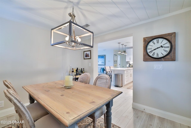 dining room with a notable chandelier, light wood-type flooring, and ornamental molding