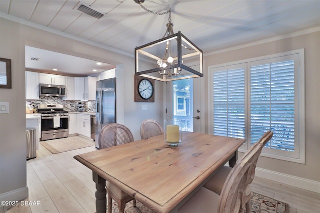 dining room featuring an inviting chandelier, light wood-type flooring, plenty of natural light, and crown molding