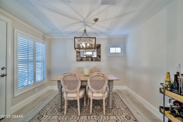 dining room with light hardwood / wood-style floors, wooden ceiling, crown molding, and a chandelier