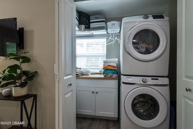 washroom with stacked washer and clothes dryer, cabinets, and dark wood-type flooring