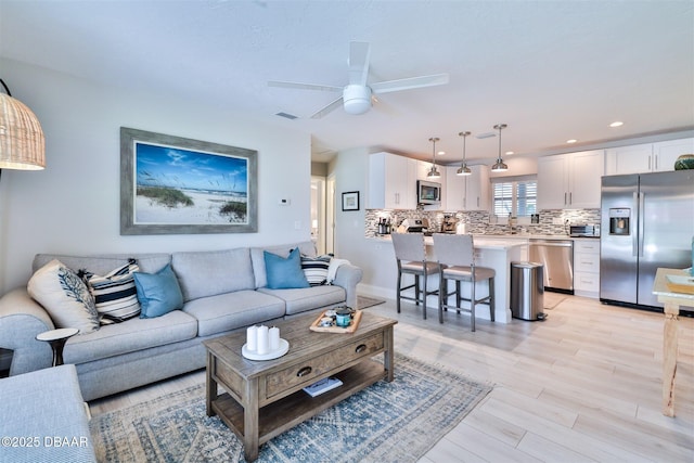 living room with ceiling fan, light hardwood / wood-style flooring, and sink