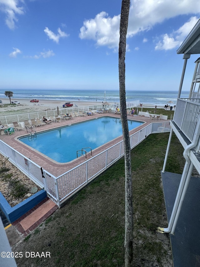 view of swimming pool featuring a water view and a lawn