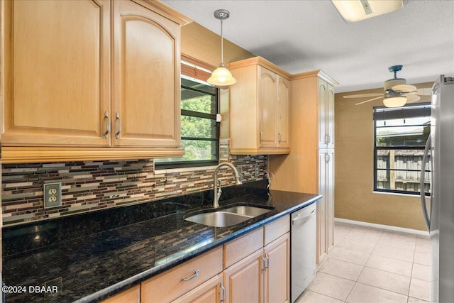 kitchen featuring sink, appliances with stainless steel finishes, dark stone counters, light brown cabinetry, and hanging light fixtures