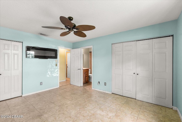 unfurnished bedroom with ceiling fan, connected bathroom, multiple closets, and a textured ceiling