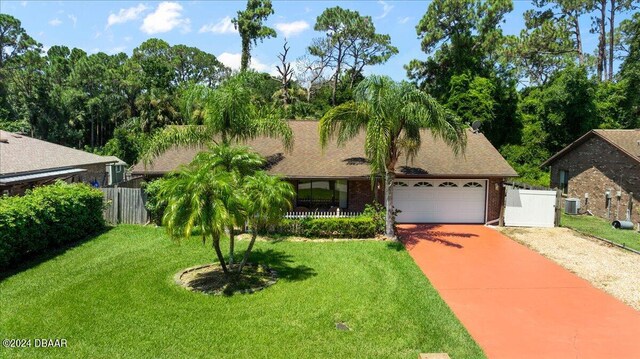 view of front of house featuring a garage, cooling unit, and a front yard