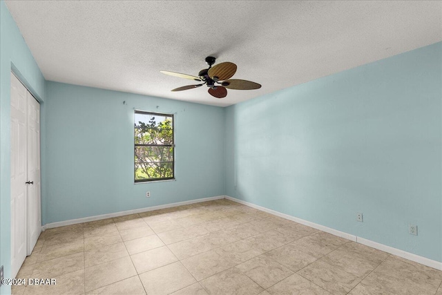 spare room featuring ceiling fan, a textured ceiling, and light tile patterned floors