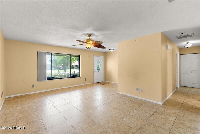 tiled empty room with a textured ceiling and ceiling fan