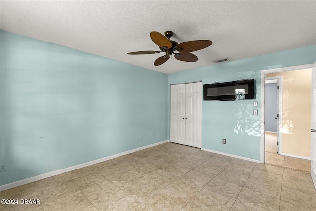 unfurnished bedroom featuring ceiling fan, a textured ceiling, and a closet