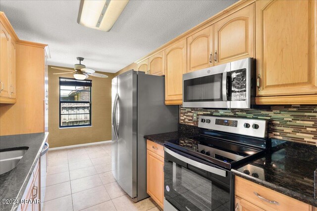 kitchen with light tile patterned flooring, appliances with stainless steel finishes, tasteful backsplash, light brown cabinets, and ceiling fan