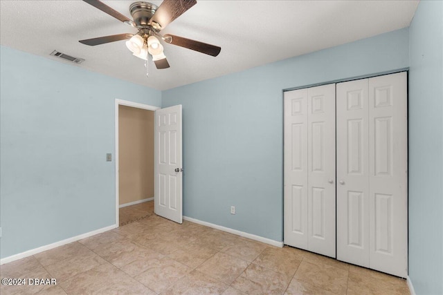 unfurnished bedroom featuring a textured ceiling, light tile patterned floors, ceiling fan, and a closet