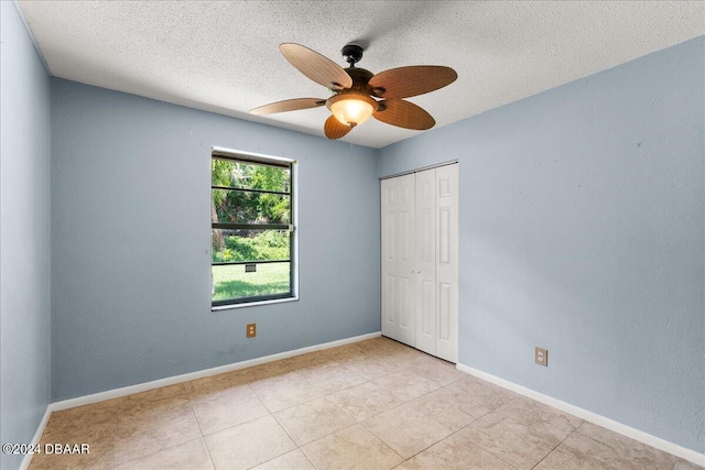 unfurnished bedroom with a closet, a textured ceiling, light tile patterned floors, and ceiling fan