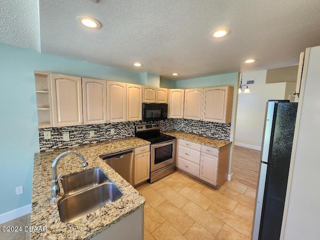 kitchen with light stone counters, stainless steel appliances, backsplash, a textured ceiling, and sink