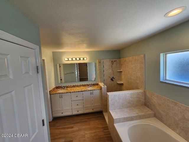 bathroom with vanity, a textured ceiling, hardwood / wood-style flooring, and separate shower and tub