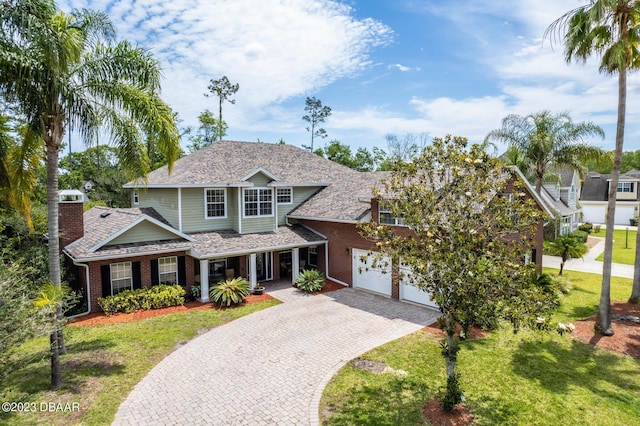 10 Foxhunter Flt, Ormond Beach, FL 32174 - view of front of property with a chimney, brick siding, decorative driveway, a front yard, and roof with shingles