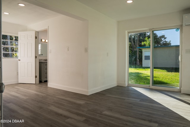 unfurnished room with dark hardwood / wood-style flooring and an AC wall unit