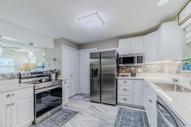 kitchen with sink, decorative light fixtures, appliances with stainless steel finishes, white cabinets, and backsplash