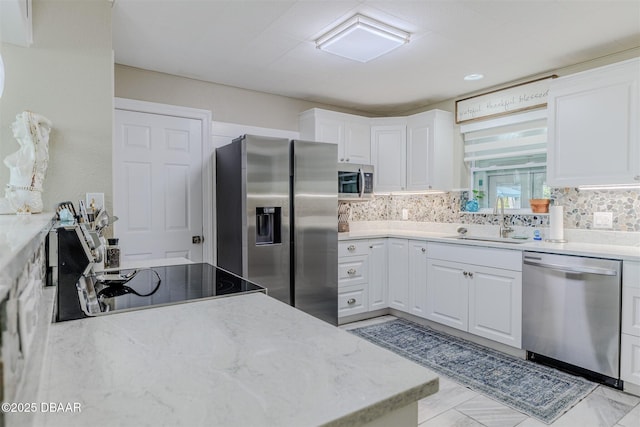 kitchen featuring sink, appliances with stainless steel finishes, white cabinetry, light stone counters, and tasteful backsplash