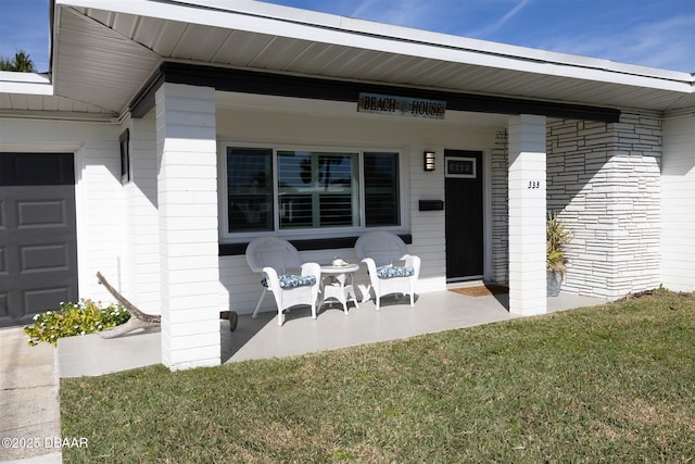 doorway to property featuring a lawn and covered porch