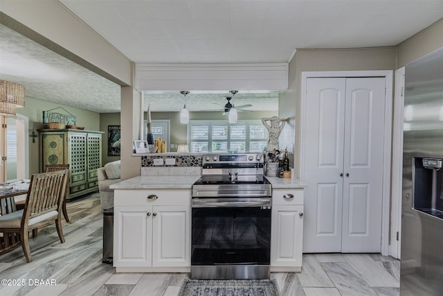 kitchen featuring pendant lighting, ceiling fan, appliances with stainless steel finishes, white cabinetry, and light stone counters