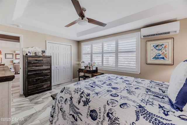 bedroom with a closet, a wall mounted AC, ceiling fan, and a tray ceiling