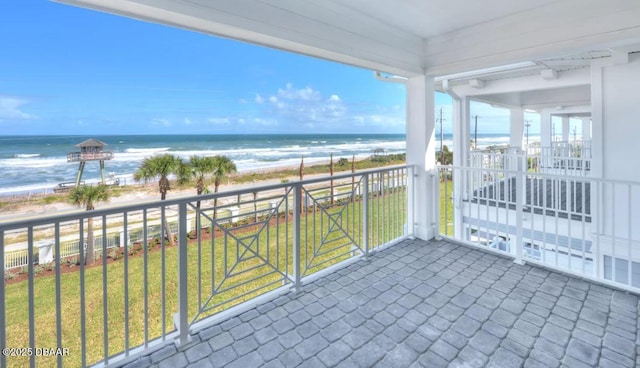 balcony with a water view and a view of the beach