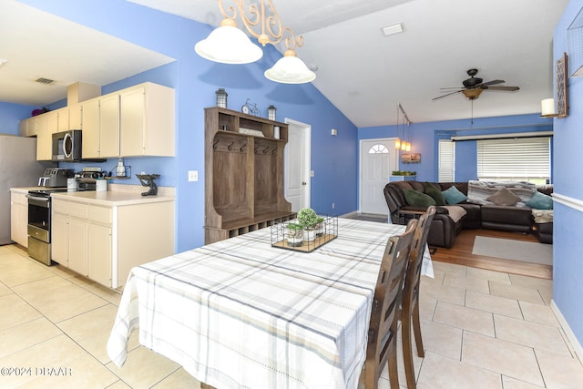 dining area with ceiling fan, light tile patterned floors, and vaulted ceiling