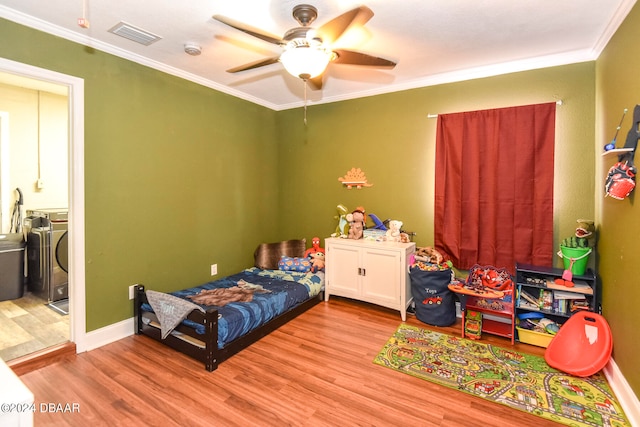 bedroom featuring washing machine and clothes dryer, ceiling fan, light wood-type flooring, and ornamental molding