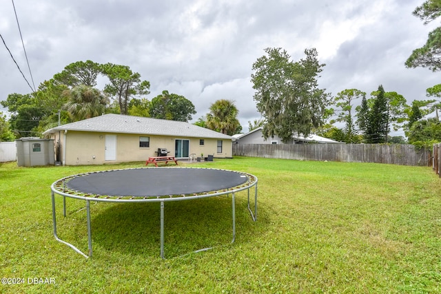 view of yard featuring a trampoline and a storage unit